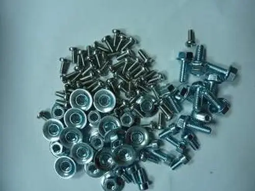 Schrauben unterschiedlicher Größen aus Metall, unsortiert, auf hellem Hintergrund. Bei einigen Teilen ist das Logo von Remeha sichtbar.